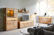 Wohnzimmer mit modernen Holzmöbeln, darunter ein Highboard, ein Lowboard und ein Sideboard, alle mit Beleuchtung. Perspektive von vorne links.
