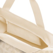 Nahaufnahme einer cremefarbenen Stofftasche mit Reißverschluss und Tragegriffen, Blick schräg von oben in das geöffnete Hauptfach vor weißem Hintergrund.