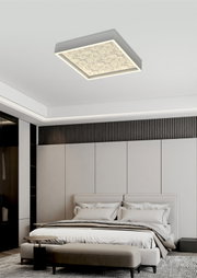 Moderne vierkante led-plafondlamp met decoratief patroon, van onderaf gezien, gemonteerd in een stijlvolle slaapkamer.