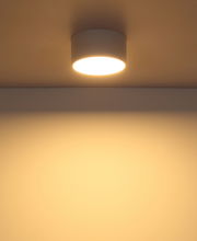 Moderne Deckenleuchte in zylindrischer Form, von unten betrachtet, mit warmem Lichtschein an der Decke.