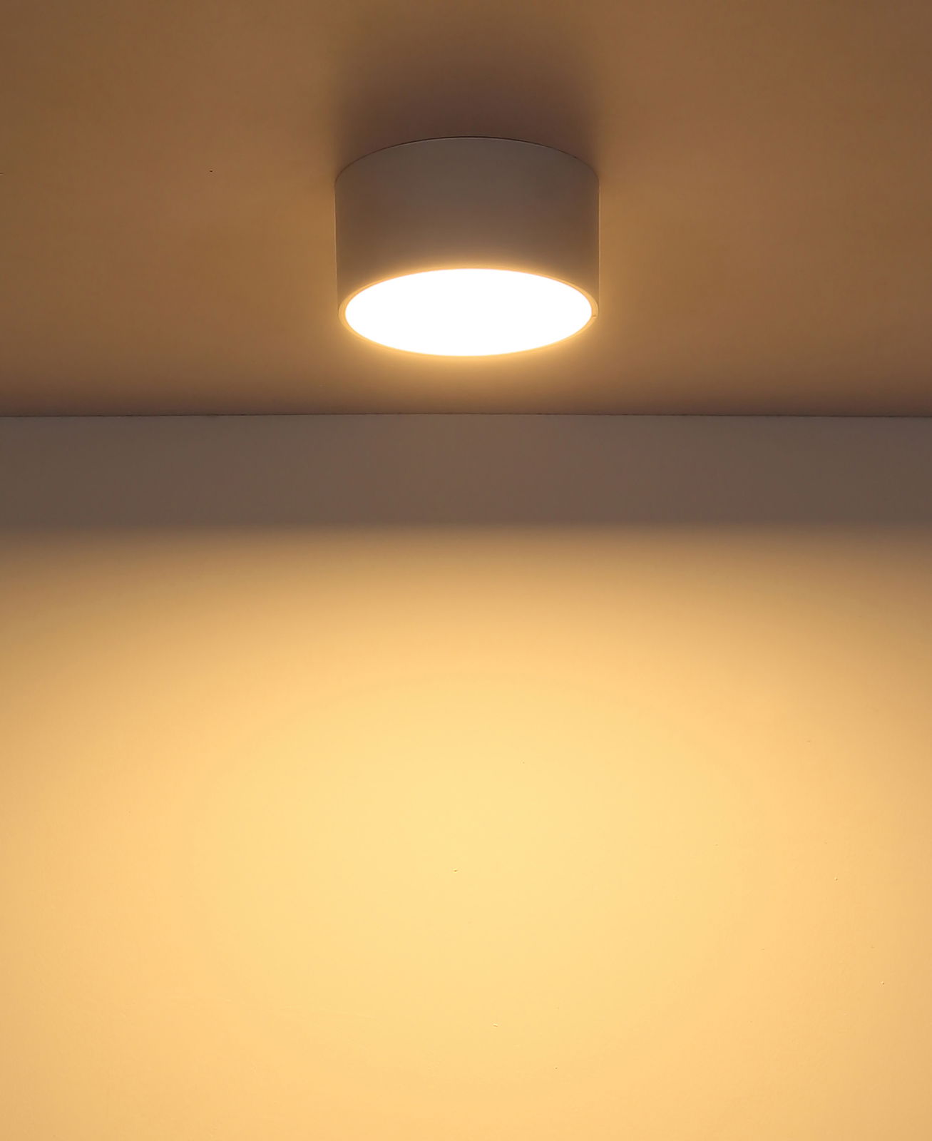 Moderne Deckenleuchte in zylindrischer Form, von unten betrachtet, mit warmem Lichtschein an der Decke.