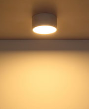 Moderne Deckenleuchte in zylindrischer Form, von unten betrachtet, mit warmem Lichtschein an der Decke.