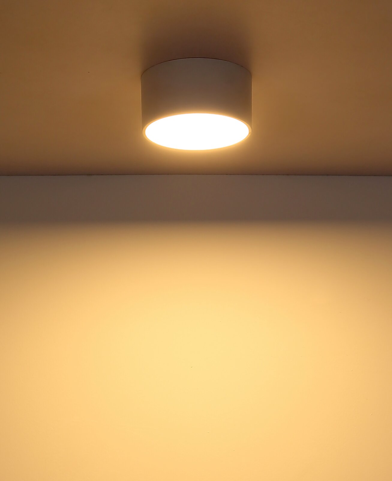 Moderne Deckenleuchte in zylindrischer Form, von unten betrachtet, mit warmem Lichtschein an der Decke.