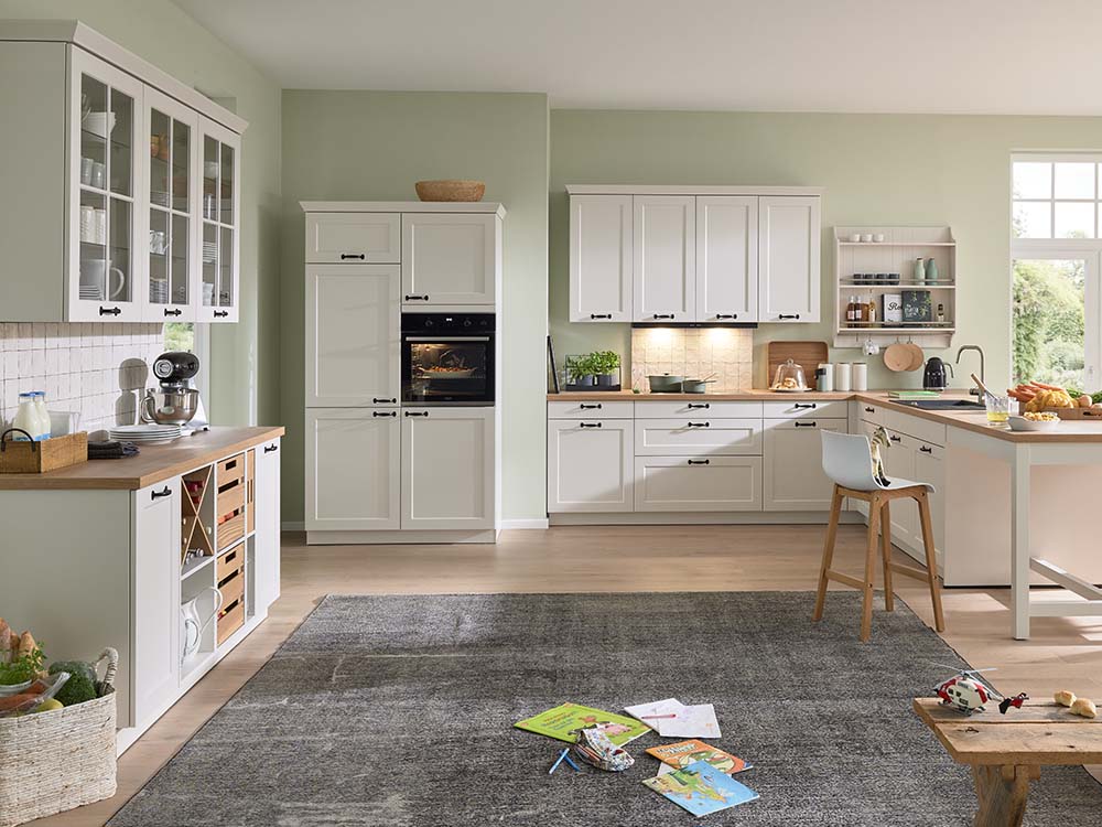 Helle Landhausküche in Weiß mit Holzdetails, Kochinsel, offenen Regalen und gemütlicher Wohnatmosphäre.