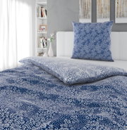 Blau-weiße Bettwäsche mit floralem Muster und passendem Kissen auf einem weißen Bett, Perspektive: schräg von vorne/leicht von oben im Schlafzimmer.