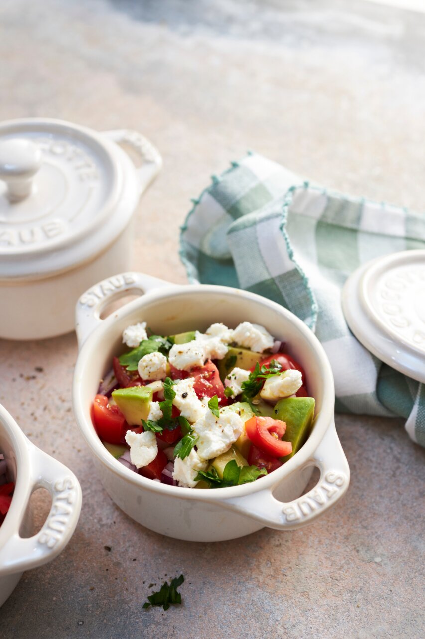 Nahaufnahme eines elfenbeinfarbenen Mini-Cocotte-Sets mit frischem Salat, fotografiert aus der Vogelperspektive.