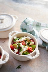 Nahaufnahme eines elfenbeinfarbenen Mini-Cocotte-Sets mit frischem Salat, fotografiert aus der Vogelperspektive.