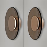 Moderne Wandleuchte PURE Moon mit runder, rauchglasfarbener Scheibe und zentralem Lichtelement, seitliche Perspektive.