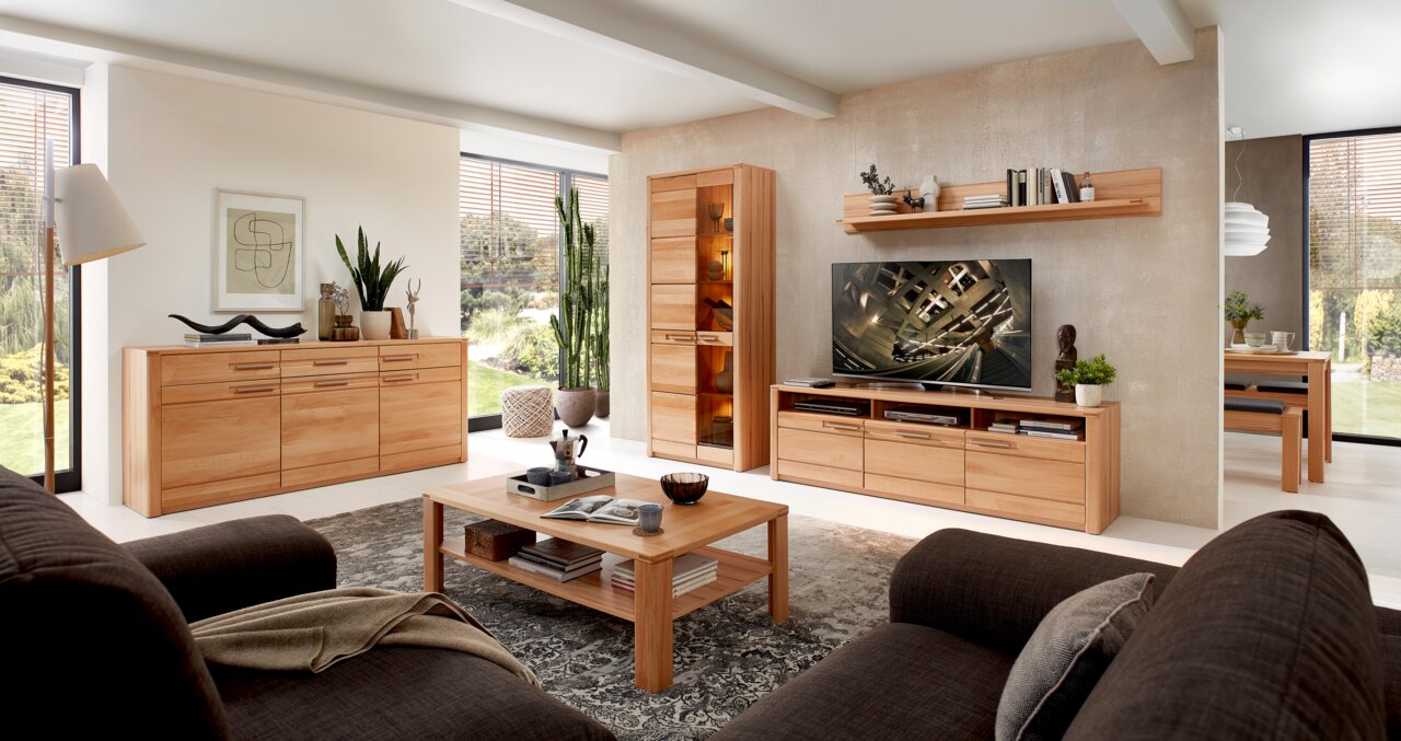 Wohnzimmer mit modernen Holzmöbeln, darunter ein TV-Lowboard, ein Couchtisch und ein Sideboard, aus der Perspektive von einem Sofa aus gesehen.