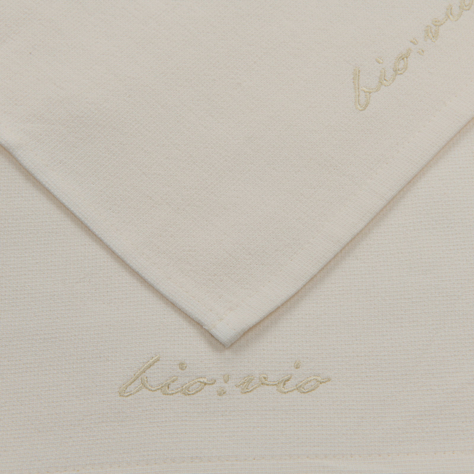 Nahaufnahme eines weißen Gästetuchsets mit dezenter Stickerei 'bio:vio' in der Ecke.