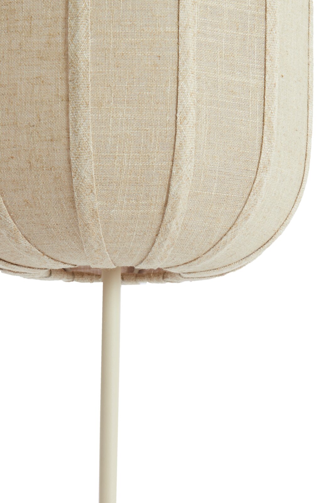 Close-up vanuit vooraanzicht van een beige stoffen lampenkap met verticale siernaden en een crèmekleurige standaard tegen een witte achtergrond