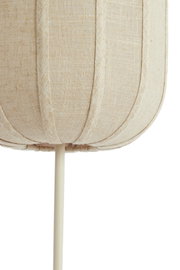 Close-up vanuit vooraanzicht van een beige stoffen lampenkap met verticale siernaden en een crèmekleurige standaard tegen een witte achtergrond
