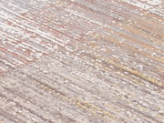 Nahaufnahme eines Designer-Teppichs mit einem modernen, mehrfarbigen Muster in Erdtönen und Pastellfarben, schräg von oben fotografiert.