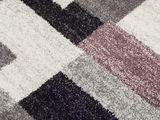 Nahaufnahme eines Frisé-Teppichs mit geometrischem Muster in Schwarz, Grau, Weiß und Lila.