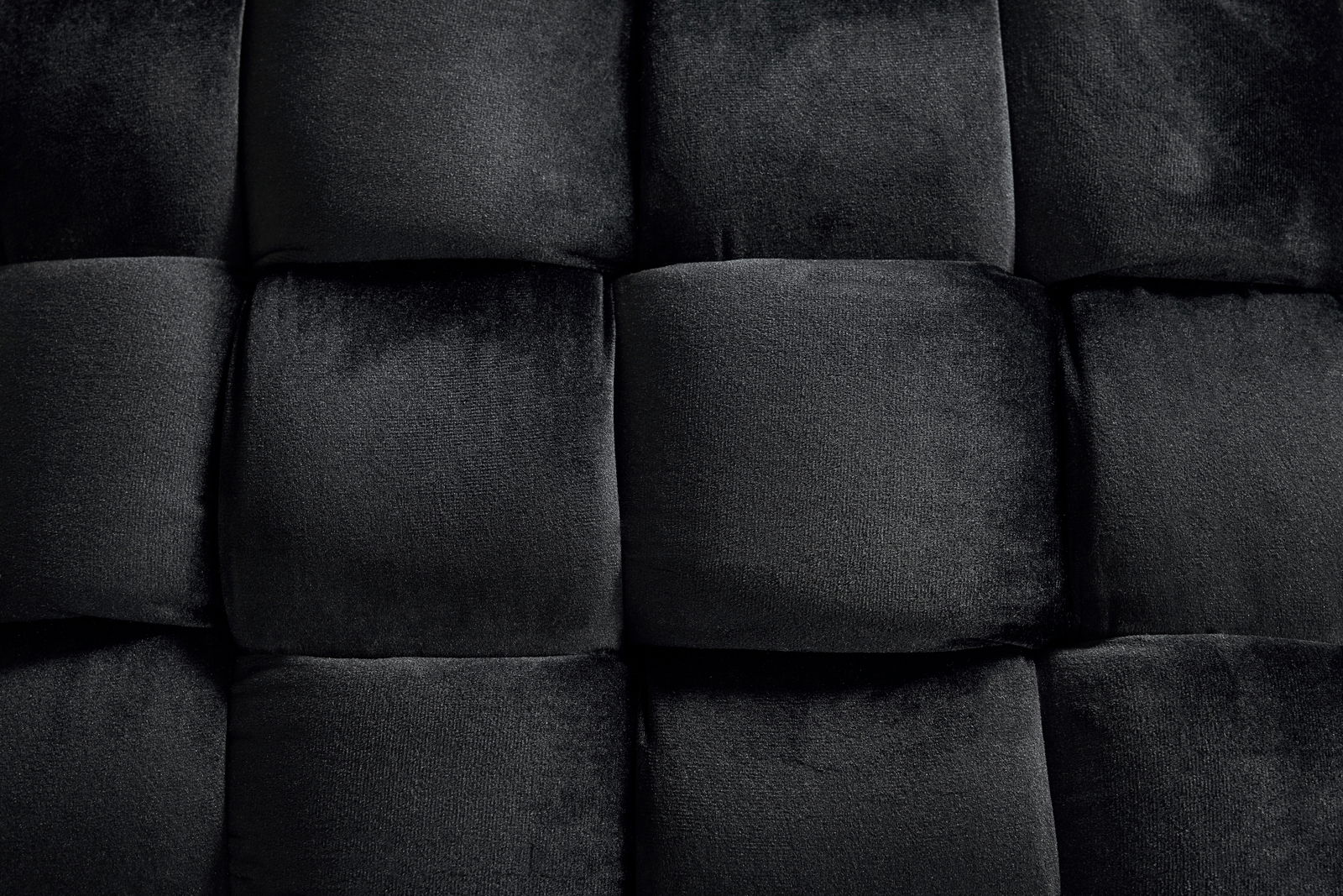 Nahaufnahme eines schwarzen, gepolsterten Hockers mit samtiger Textur, von oben betrachtet.