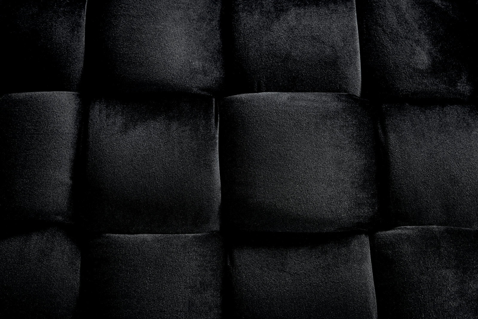 Nahaufnahme eines schwarzen, gepolsterten Hockers mit samtiger Textur, von oben betrachtet.