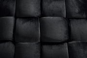 Nahaufnahme eines schwarzen, gepolsterten Hockers mit samtiger Textur, von oben betrachtet.