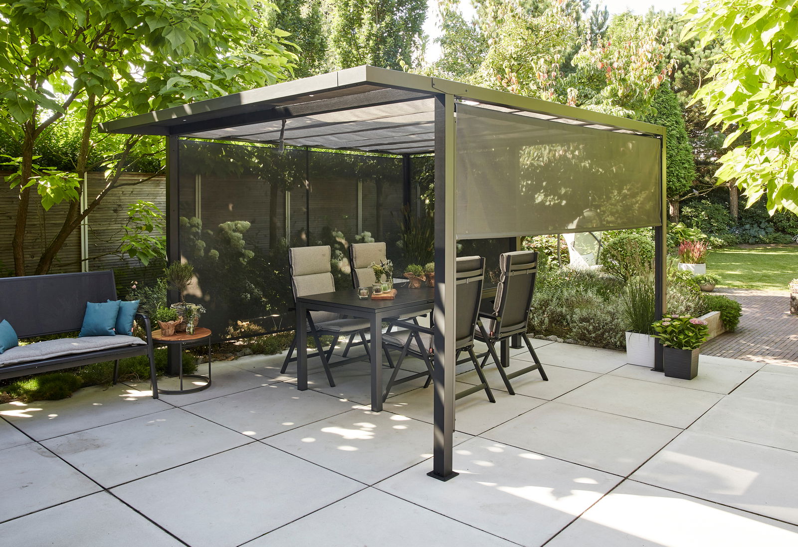 Moderne Pergola mit Faltdach und Sichtschutz in einem sonnigen Garten, seitliche Perspektive