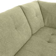 Nahaufnahme einer grünen Sofaecke mit gepolsterten Kissen und strukturierter Oberfläche, Perspektive von oben.