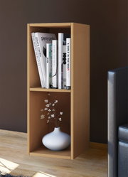 Schmales, offenes Bücherregal aus hellem Holz mit zwei Fächern, oben mit Büchern und unten mit weißer Vase mit Zweigen, im Wohnzimmer neben einem Sofa, Perspektive: frontale Ansicht leicht von rechts.