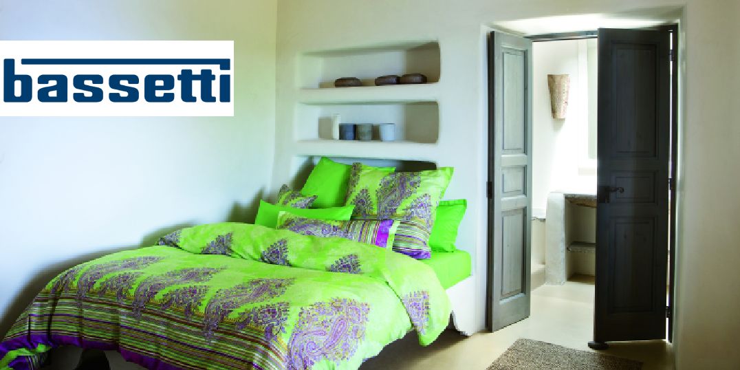 Ein helles Schlafzimmer mit einer leuchtend grün gemusterten und Bassetti-Logo auf der Oberseite.