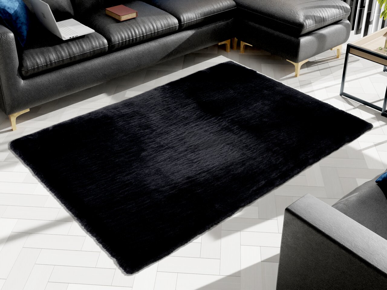 Schwarzer Fellteppich in einem modernen Wohnzimmer, von oben betrachtet, umgeben von einem dunklen Ledersofa.