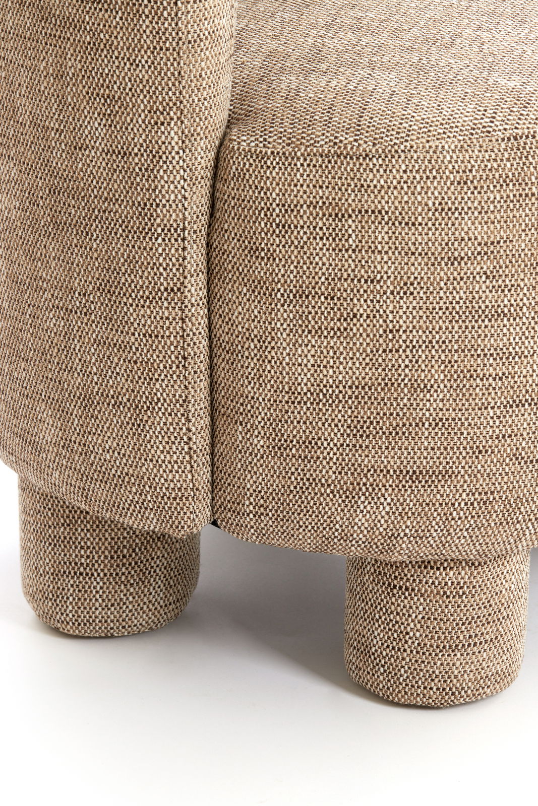Nahaufnahme eines Sessels mit beigem Stoffbezug und runden Beinen, seitliche Perspektive