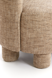 Nahaufnahme eines Sessels mit beigem Stoffbezug und runden Beinen, seitliche Perspektive