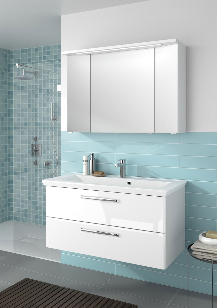 Moderner weißer Badblock mit zwei Schubladen und integriertem Waschbecken, frontal betrachtet, vor einer Wand mit blauen Fliesen.