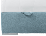 Nahaufnahme eines Boxspringbetts mit hellblauem Stoffbezug und weißer Matratze, seitliche Perspektive