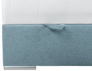 Nahaufnahme eines Boxspringbetts mit hellblauem Stoffbezug und weißer Matratze, seitliche Perspektive