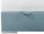 Nahaufnahme eines Boxspringbetts mit hellblauem Stoffbezug und weißer Matratze, seitliche Perspektive