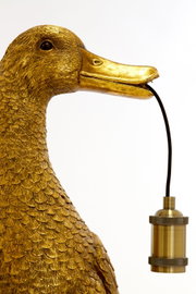 Gouden tafellamp in de vorm van een eend, die een lampvoet in zijn snavel houdt, zijaanzicht.