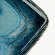 Detailaufnahme einer ovalen Kunstharz-Servierplatte mit blau-türkiser Marmorierung und goldenen Akzenten, schräg von oben fotografiert