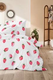 Weißer Bettbezug mit pink-rotem Erdbeer-Muster auf gemachtem Bett im Schlafzimmer, Frontansicht leicht seitlich von vorne