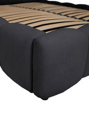 Nahaufnahme eines Polsterbettgestells in dunklem Stoff, seitliche Perspektive