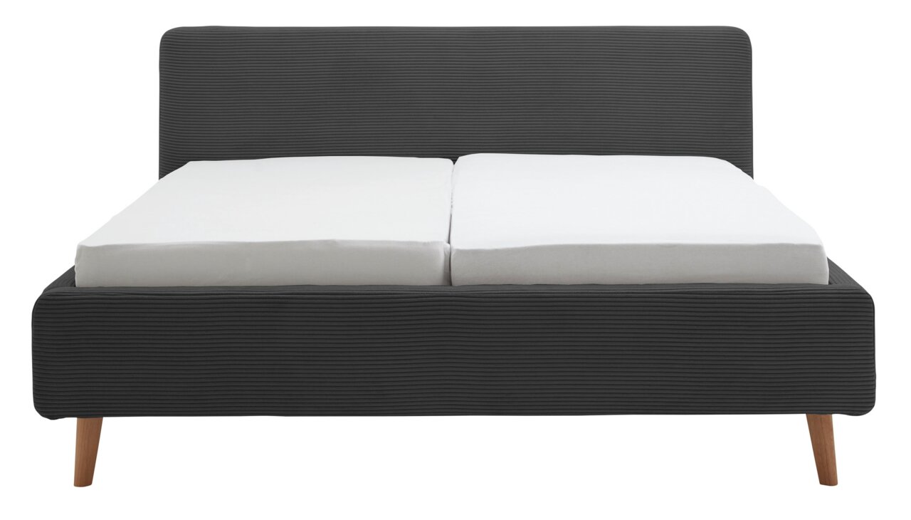 Vooraanzicht van een gestoffeerd bedframe met een donkergrijze stoffen bekleding en houten poten.