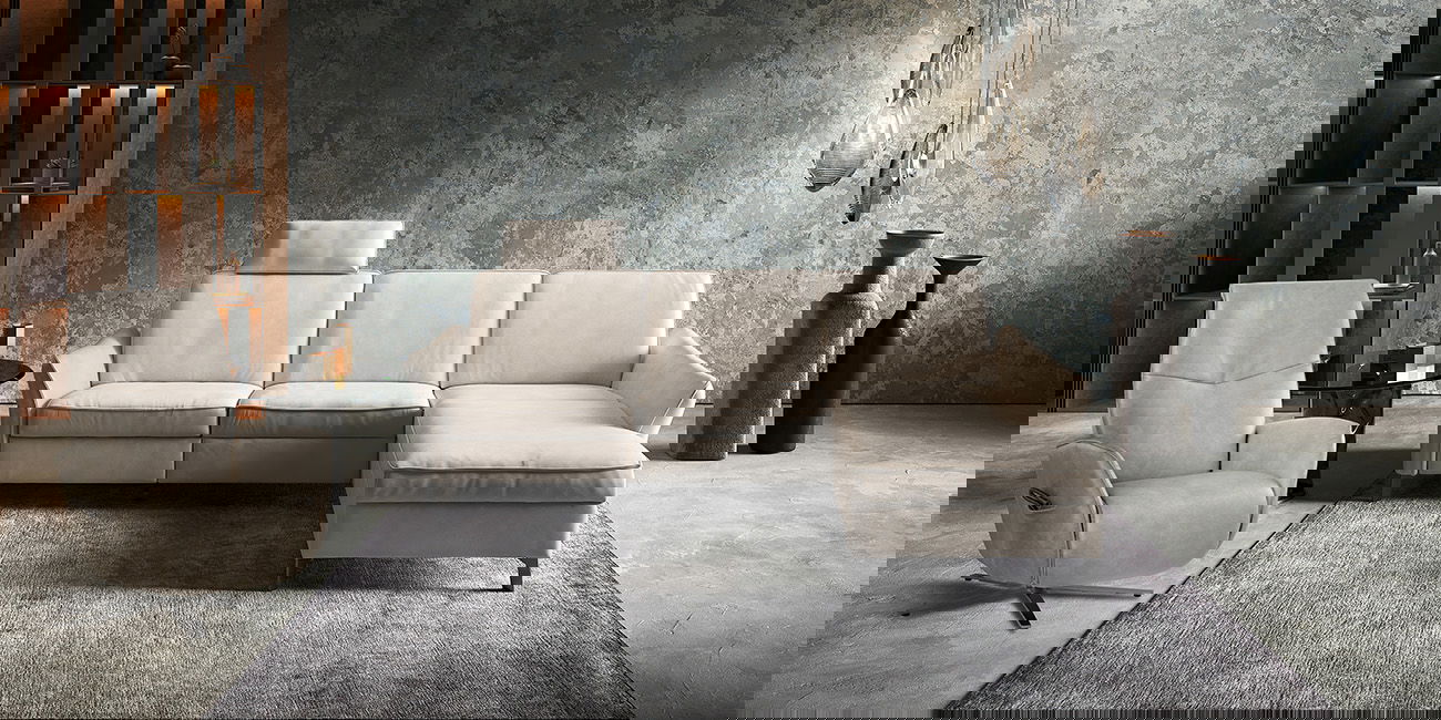 Ein helles Sofa und ein Sessel stehen auf einem Teppich in einem ruhig gestalteten Raum.