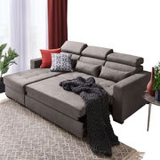 Graue Rundecke mit verstellbaren Kopfstützen, dekoriert mit Kissen und Decke, aus der Perspektive von vorne links.