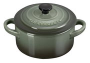 Grüne Mini-Cocotte von Le Creuset mit Deckel und zwei Griffen, aus schräger Perspektive fotografiert.