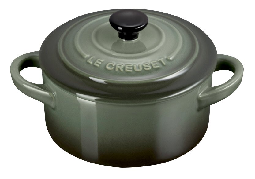 Grüne Mini-Cocotte von Le Creuset mit Deckel und zwei Griffen, aus schräger Perspektive fotografiert.