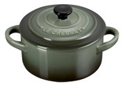 Grüne Mini-Cocotte von Le Creuset mit Deckel und zwei Griffen, aus schräger Perspektive fotografiert.