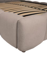 Nahaufnahme eines Polsterbettgestells in Beige mit Holzlattenrost, seitliche Perspektive.