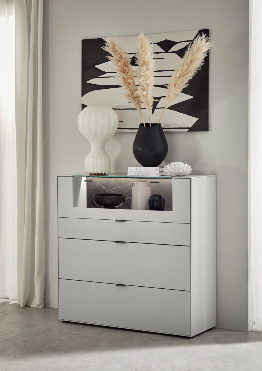 Dieter Knoll Highboard MONTESA Modernes Highboard in Weiß mit drei Schubladen, dekoriert mit einer schwarzen Vase und Pampasgras, aus seitlicher Perspektive fotografiert.