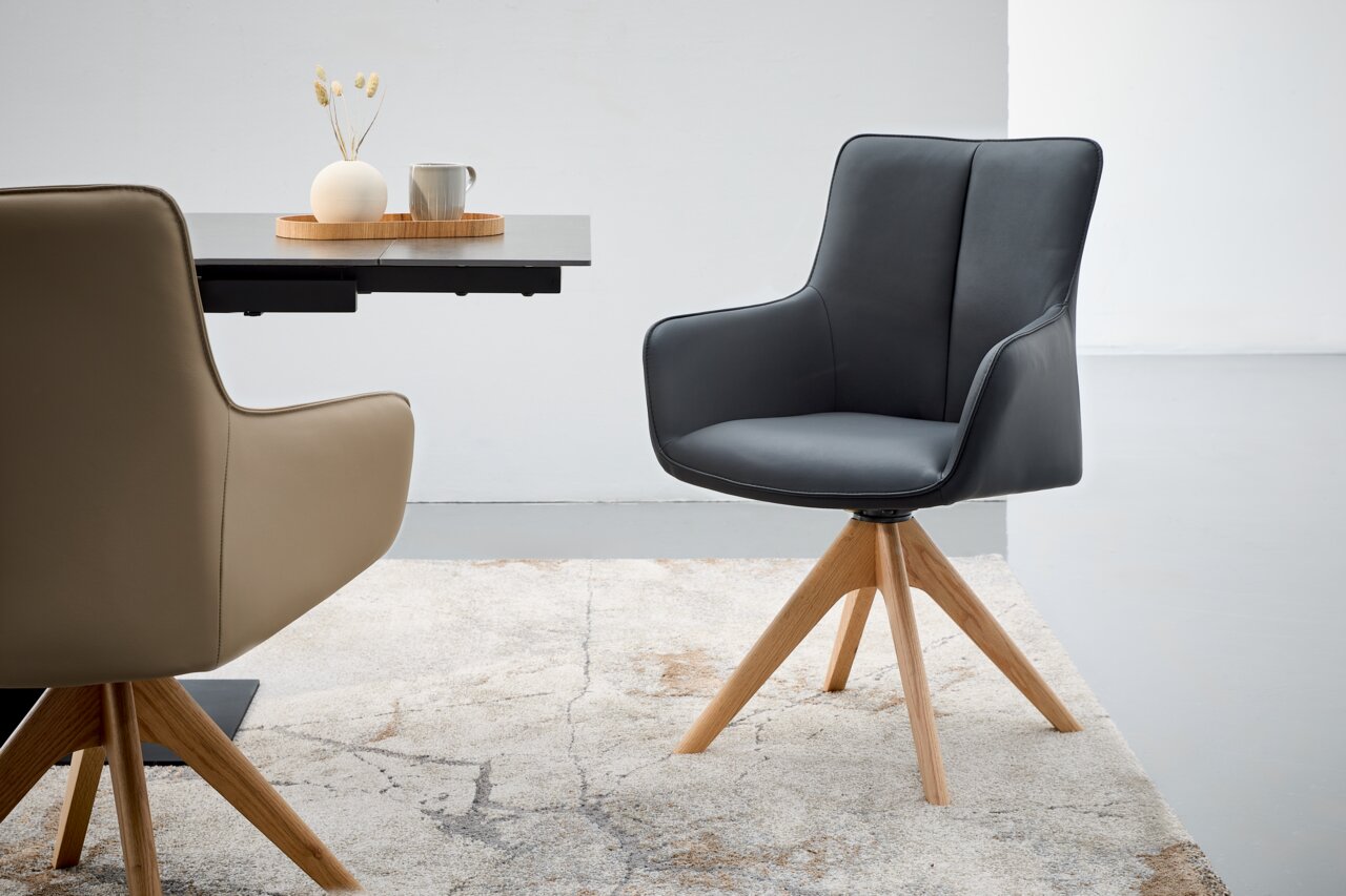 Moderner Armlehnstuhl mit schwarzem Bezug und Holzbeinen, seitliche Perspektive.