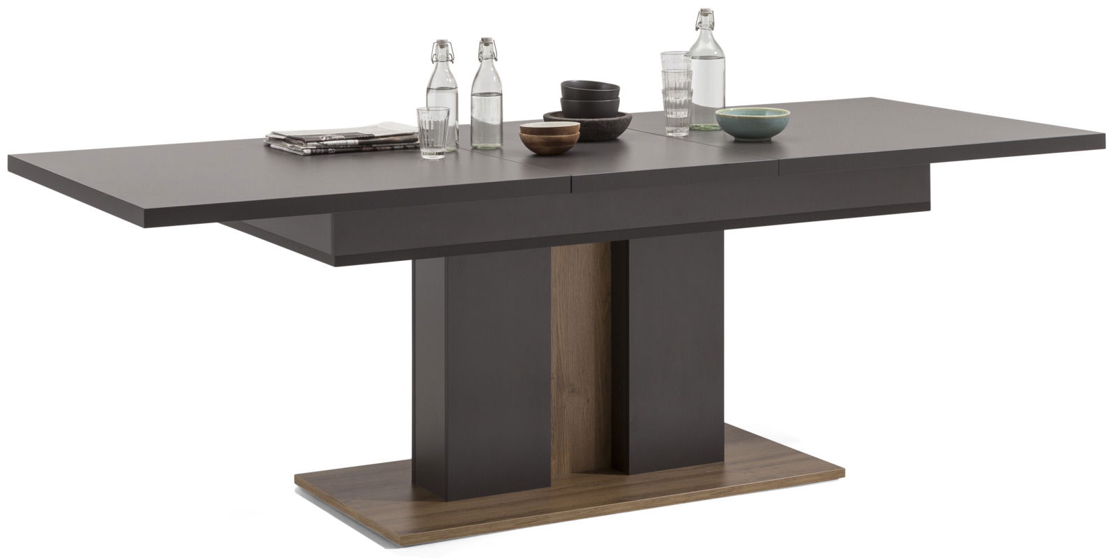 Moderner, ausziehbarer Esstisch in dunklem Holzdesign, seitliche Perspektive, dekoriert mit Geschirr und Wasserflaschen.