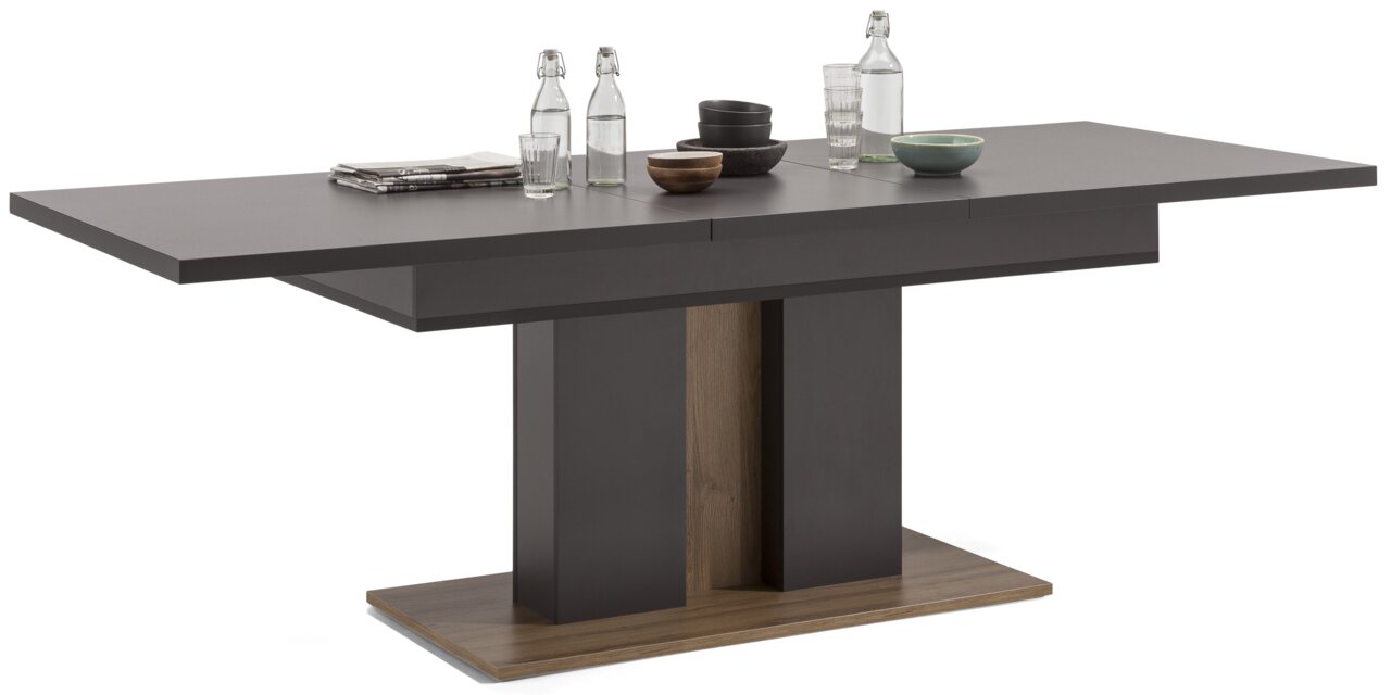 Moderner, ausziehbarer Esstisch in dunklem Holzdesign, seitliche Perspektive, dekoriert mit Geschirr und Wasserflaschen.