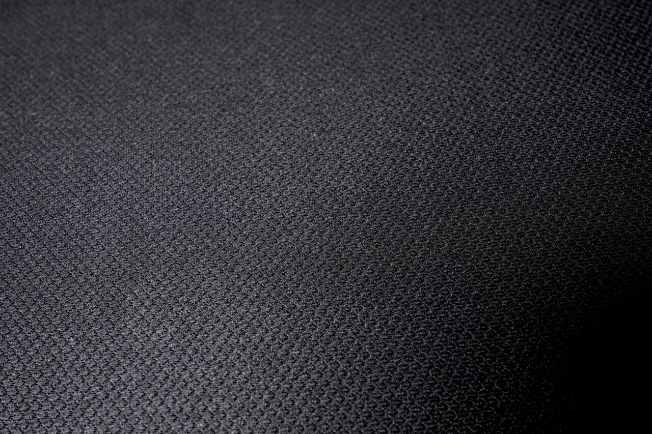 Nahaufnahme eines schwarzen Stoffbezugs mit feiner Textur, von oben betrachtet.