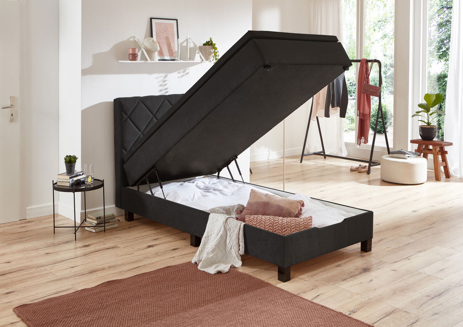 Boxbett mit hochgeklappter Matratze, seitliche Perspektive, zeigt Stauraum darunter.