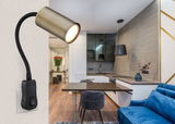 Wandleuchte in Altmessing mit flexiblem Arm, montiert an einer Wand in einem modernen Wohnzimmer mit Blick auf eine Küche.
